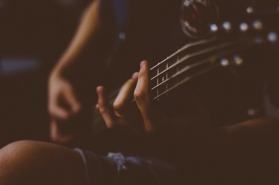 Frau mit Gitarre, Finger in Nahaufnahme, Hintergrund verschwommen (Bild: Pexels auf Pixabay)
